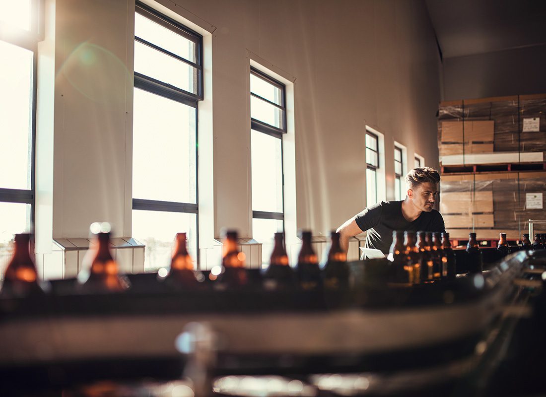 Insurance Solutions - View of a Brewery Owner Inspecting Quality of his Product in a Beer Production Facility with Bright Windows